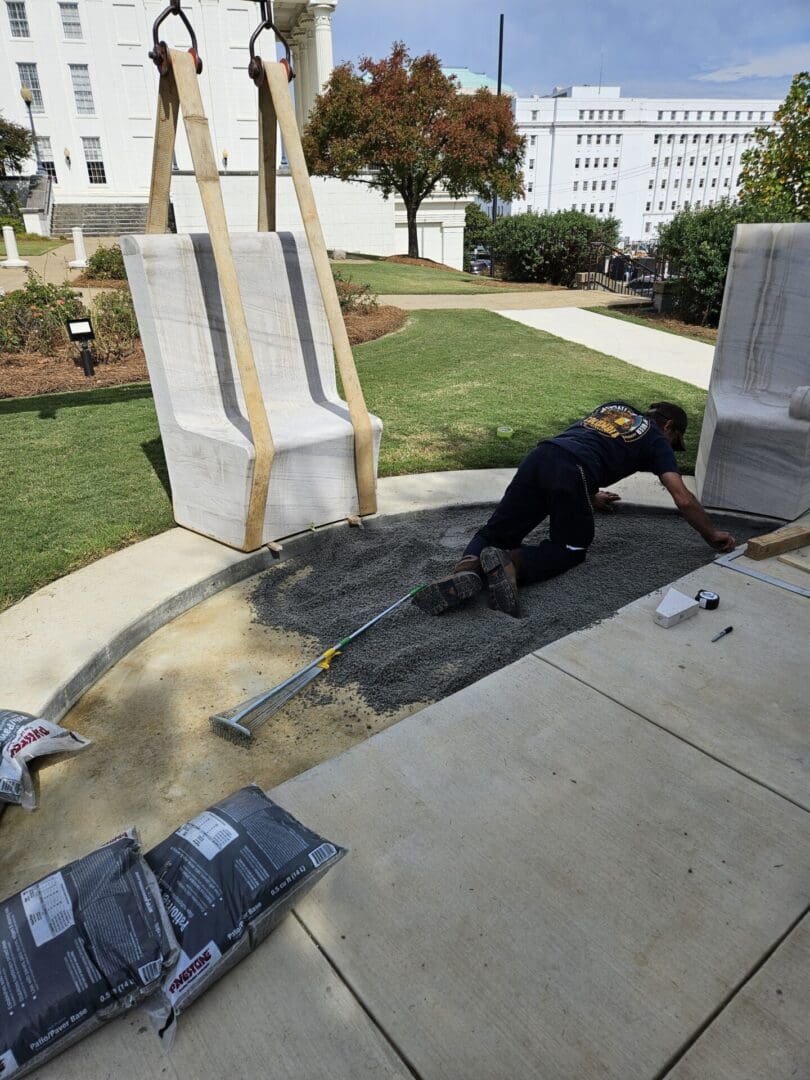 Crew guiding a curved marble panel into place by crane on capitol grounds