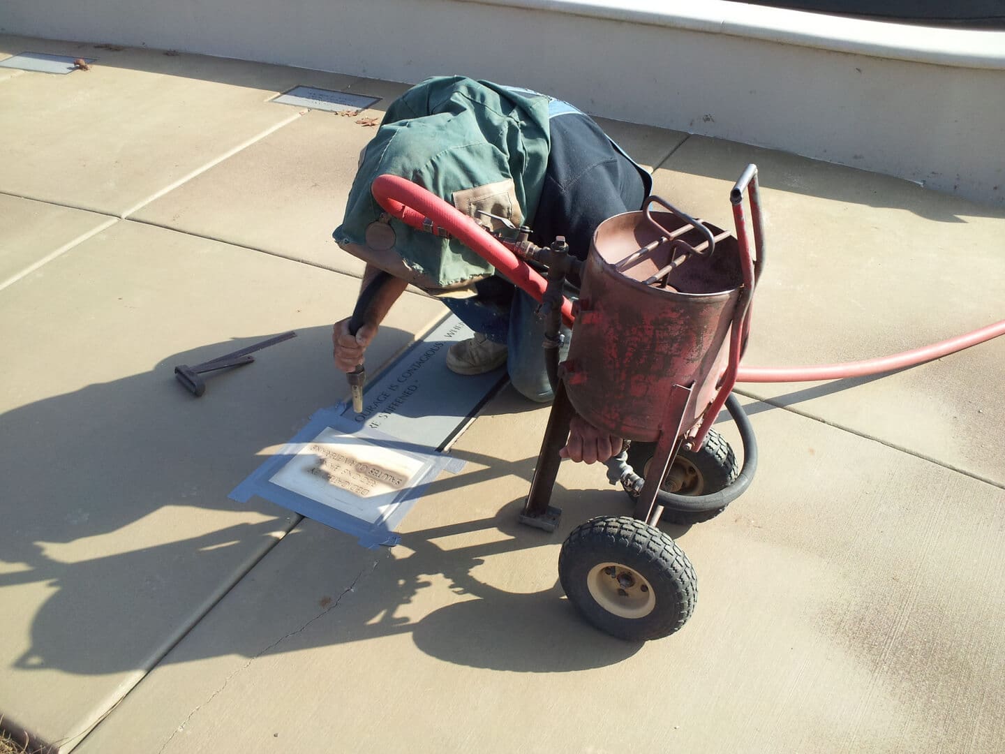 A man working on a flat marker where it lies, with a compressor cart beside him