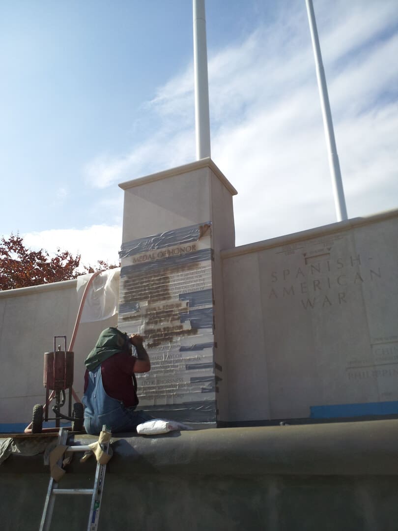 A mausoleum under construction with a worker on a ladder against the stonework